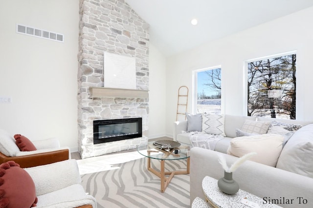 living room with a stone fireplace and lofted ceiling