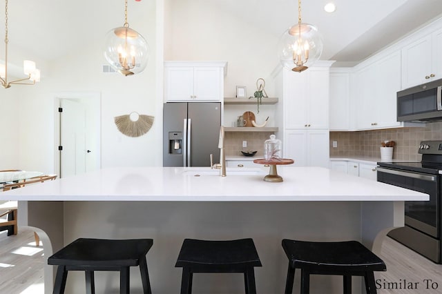 kitchen featuring white cabinets, stainless steel appliances, decorative light fixtures, and a chandelier