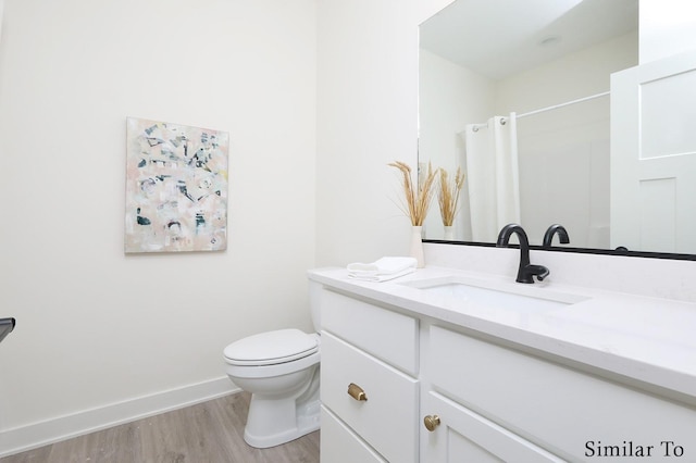 bathroom featuring toilet, hardwood / wood-style flooring, curtained shower, and vanity