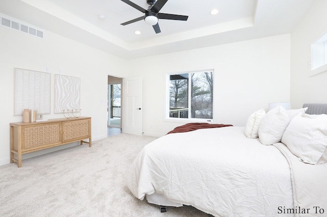 bedroom featuring a raised ceiling, ceiling fan, and carpet