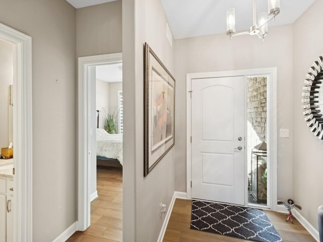 foyer with light wood-type flooring, a chandelier, and plenty of natural light