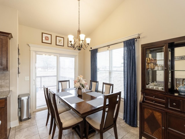 tiled dining space with lofted ceiling and a chandelier