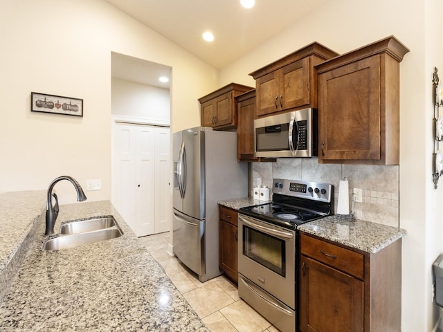 kitchen with sink, vaulted ceiling, tasteful backsplash, light stone countertops, and appliances with stainless steel finishes