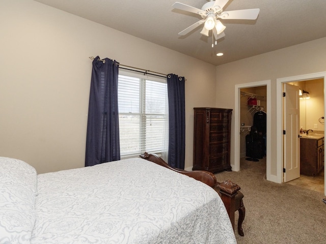 carpeted bedroom featuring a closet, ensuite bath, ceiling fan, a spacious closet, and sink