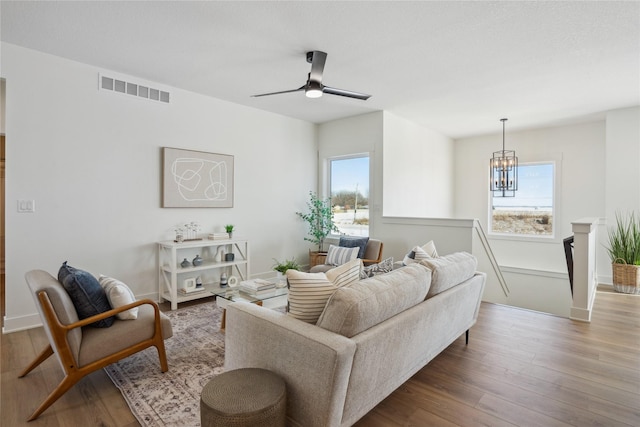 living room featuring ceiling fan with notable chandelier, wood-type flooring, and a healthy amount of sunlight