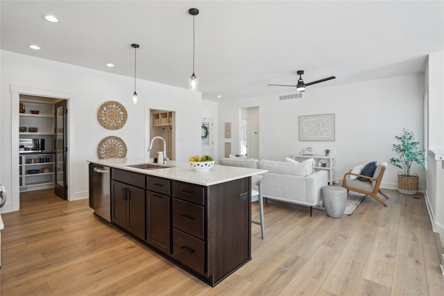 kitchen featuring stainless steel dishwasher, hanging light fixtures, a kitchen island with sink, dark brown cabinets, and sink