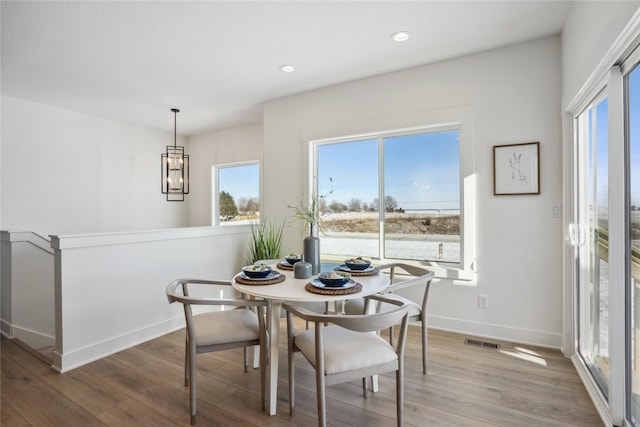 dining space featuring a healthy amount of sunlight, light hardwood / wood-style floors, and a notable chandelier