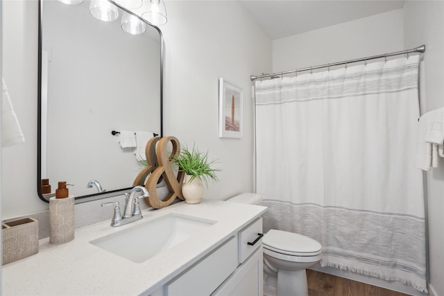 bathroom with hardwood / wood-style floors, toilet, curtained shower, and vanity