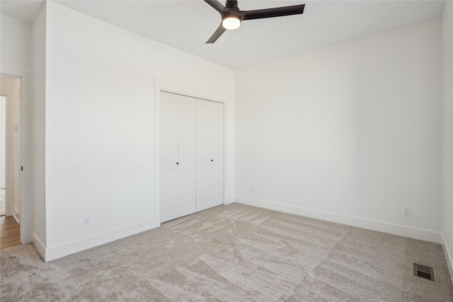 unfurnished bedroom featuring a closet, ceiling fan, and light colored carpet