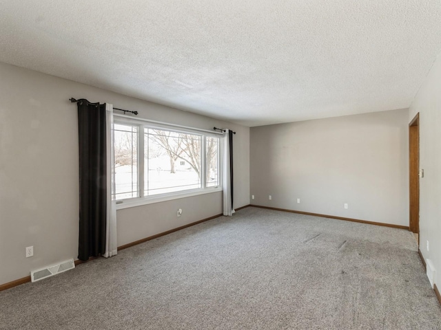 empty room with light colored carpet and a textured ceiling