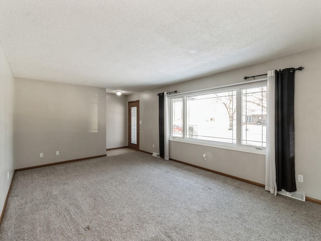 carpeted empty room featuring a textured ceiling