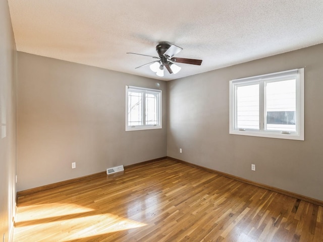 spare room featuring light wood-type flooring, ceiling fan, and a textured ceiling