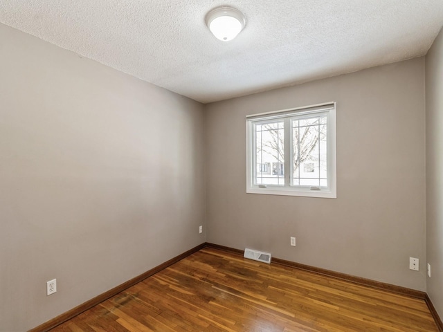 empty room featuring a textured ceiling and dark hardwood / wood-style flooring