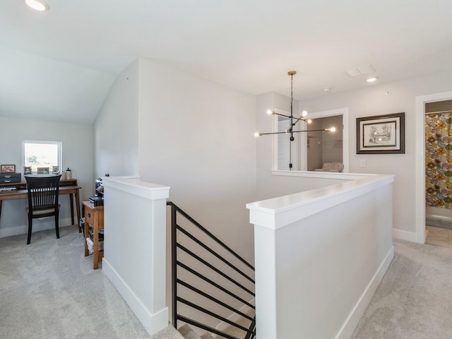 hall featuring lofted ceiling, light colored carpet, and an inviting chandelier