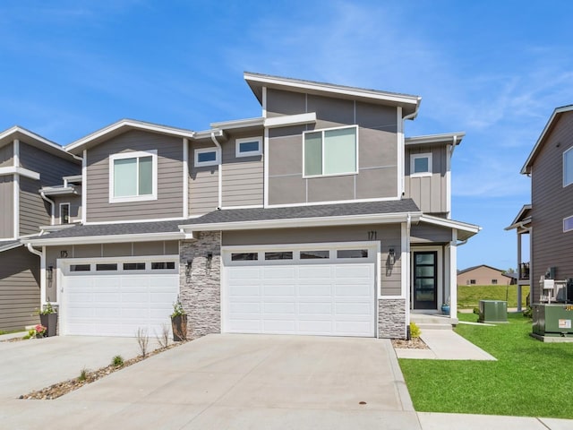 view of front of home featuring central AC unit, a front lawn, and a garage