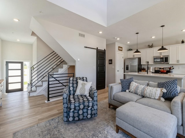 living room featuring sink, light hardwood / wood-style flooring, and a barn door