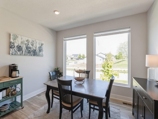 dining space featuring a textured ceiling and light wood-type flooring