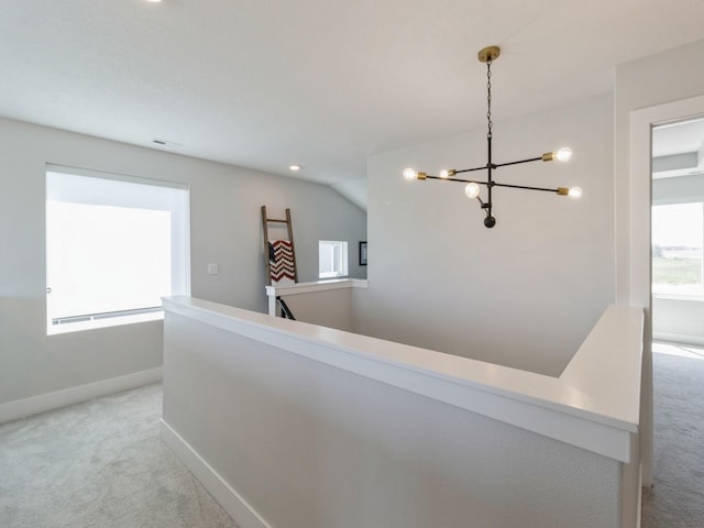 corridor featuring lofted ceiling, light carpet, and a chandelier