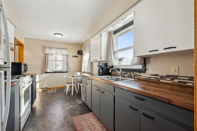 kitchen with butcher block counters, white range with gas cooktop, decorative backsplash, white cabinets, and sink