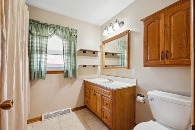 bathroom with toilet, vanity, and tile patterned flooring