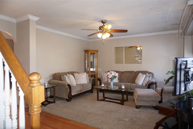 living room featuring crown molding, a ceiling fan, arched walkways, and stairs
