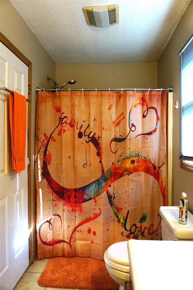 bathroom featuring a textured ceiling, toilet, walk in shower, and tile patterned flooring