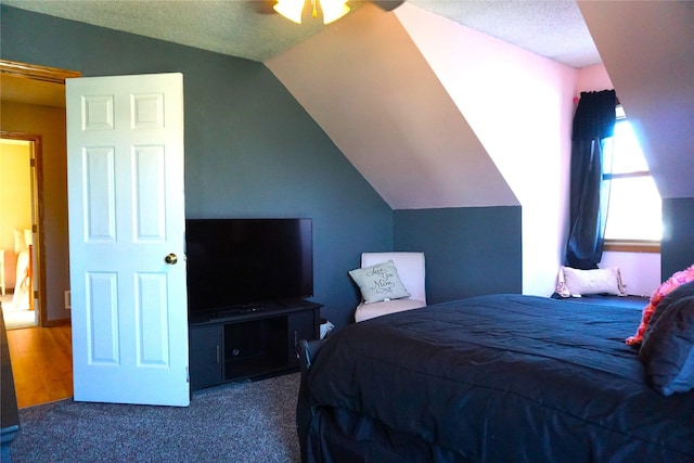 carpeted bedroom featuring vaulted ceiling, ceiling fan, and a textured ceiling