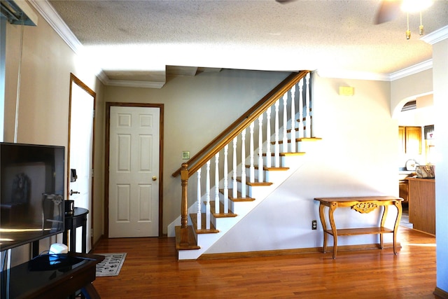 staircase with crown molding, a textured ceiling, and hardwood / wood-style flooring