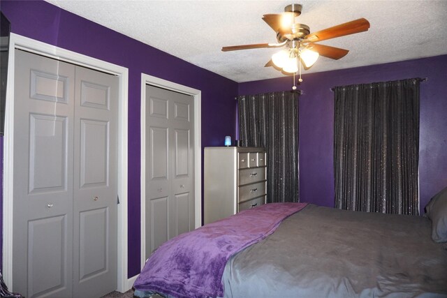 bedroom with a textured ceiling, two closets, and a ceiling fan