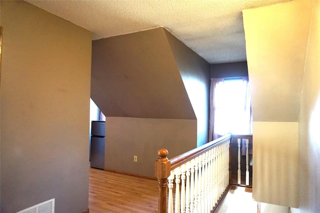 staircase with lofted ceiling, a textured ceiling, and hardwood / wood-style floors