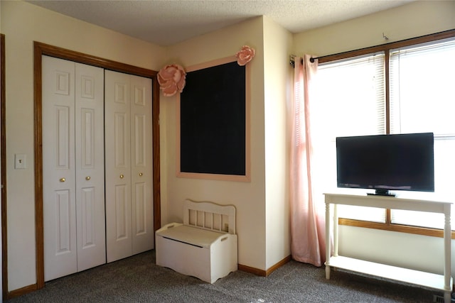 unfurnished bedroom featuring a textured ceiling, a closet, and dark colored carpet