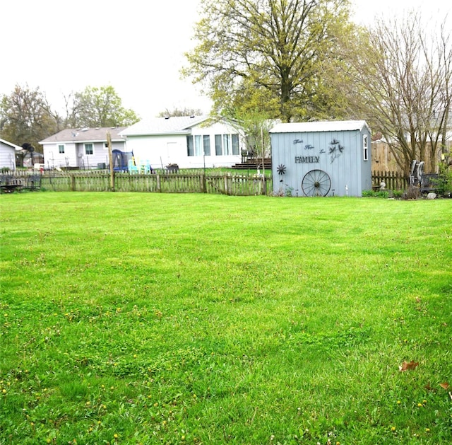 view of yard with fence, an outdoor structure, and a shed