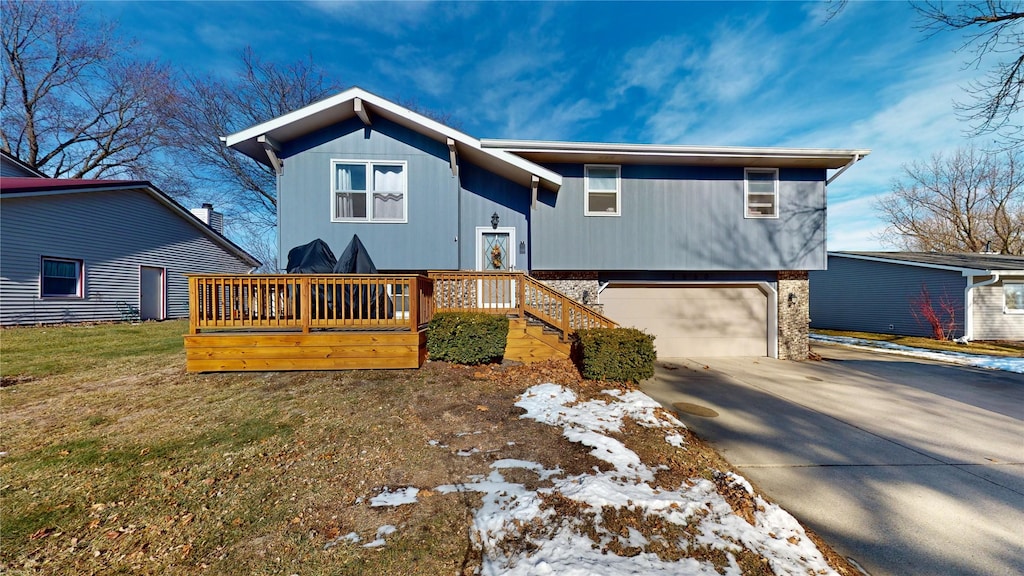 raised ranch with a front yard, a garage, and a wooden deck