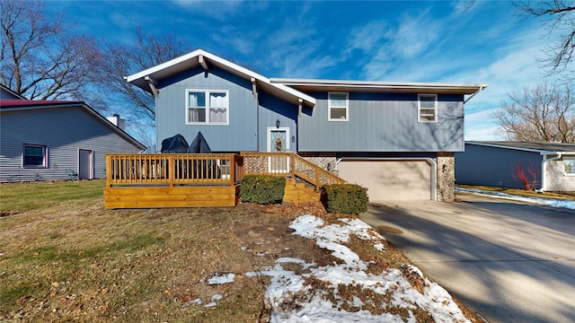 raised ranch with a front yard, a garage, and a wooden deck