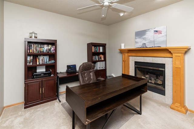 carpeted office space featuring ceiling fan and a fireplace