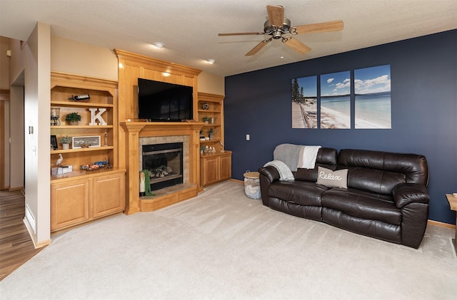 carpeted living room with ceiling fan and a tiled fireplace