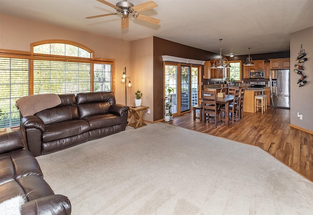 carpeted living room with ceiling fan with notable chandelier