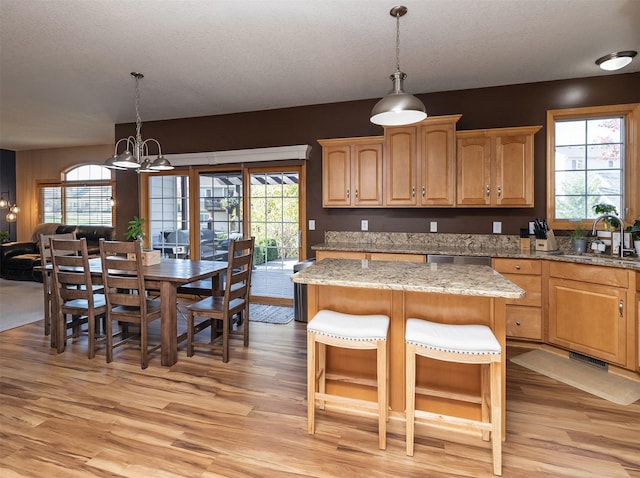 kitchen with a notable chandelier, a kitchen island, pendant lighting, and sink