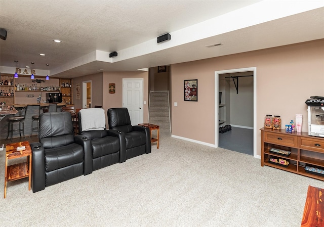 carpeted home theater featuring a textured ceiling and indoor bar