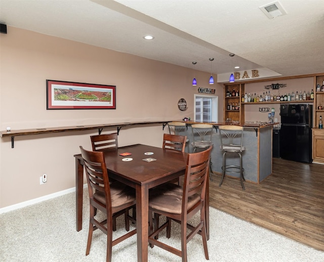 dining room featuring indoor bar and light hardwood / wood-style floors