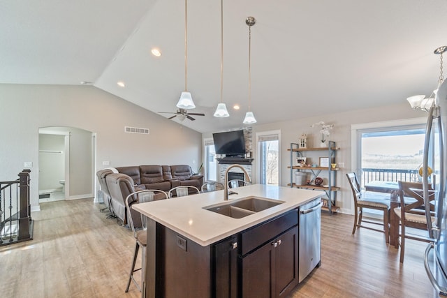 kitchen with pendant lighting, dishwasher, sink, a kitchen island with sink, and vaulted ceiling