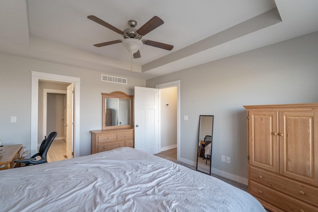 bedroom with ceiling fan and a tray ceiling