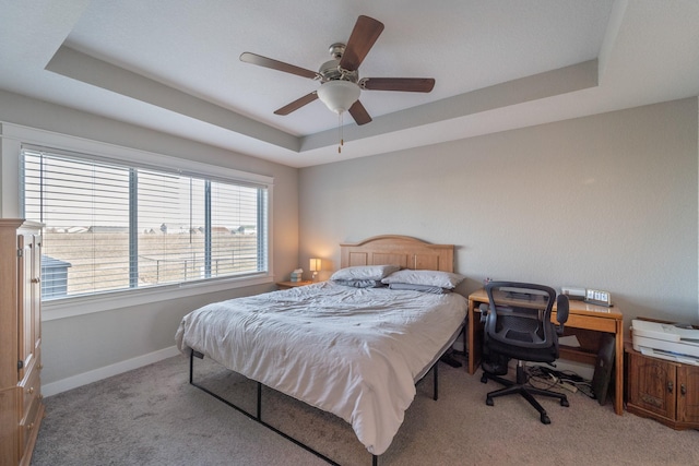 bedroom with ceiling fan, light colored carpet, and a raised ceiling