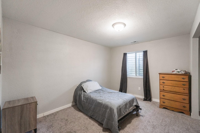 bedroom with light colored carpet and a textured ceiling