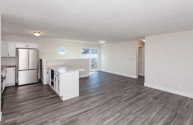 kitchen featuring a textured ceiling, white cabinetry, dark hardwood / wood-style flooring, kitchen peninsula, and stainless steel refrigerator