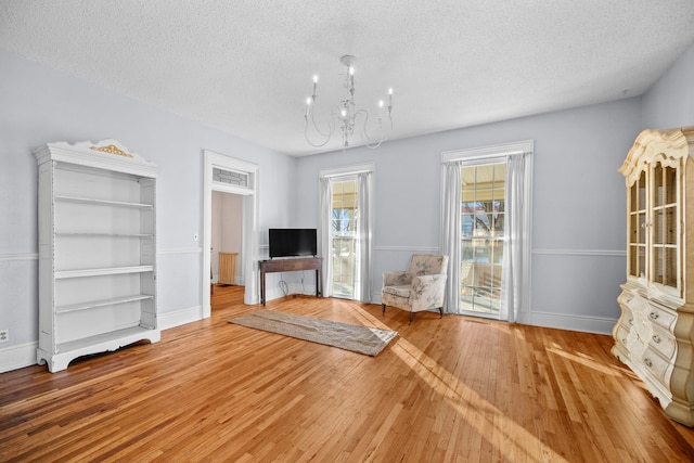 unfurnished living room featuring hardwood / wood-style flooring, a textured ceiling, built in features, and a chandelier