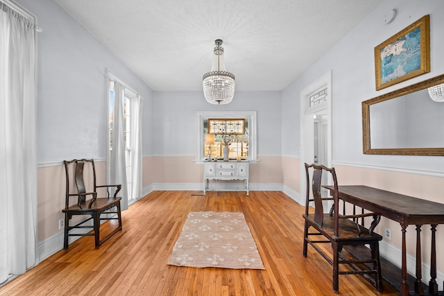 living area with a textured ceiling, a chandelier, and light hardwood / wood-style flooring