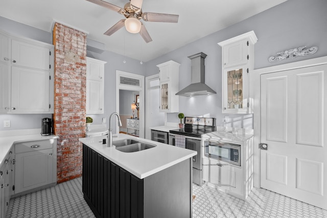 kitchen featuring an island with sink, appliances with stainless steel finishes, wall chimney exhaust hood, white cabinets, and sink