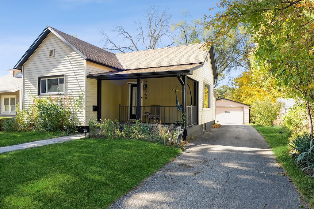 view of front of property with a garage, a front lawn, a porch, and an outbuilding