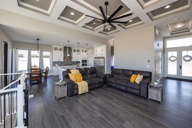 living room with ceiling fan, beam ceiling, a high ceiling, coffered ceiling, and dark hardwood / wood-style flooring